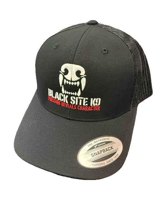 A black trucker-style snapback cap with a white embroidered skull graphic blacksitek9 logo