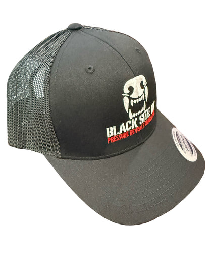 A black trucker-style snapback cap with a white embroidered skull graphic blacksitek9 logo